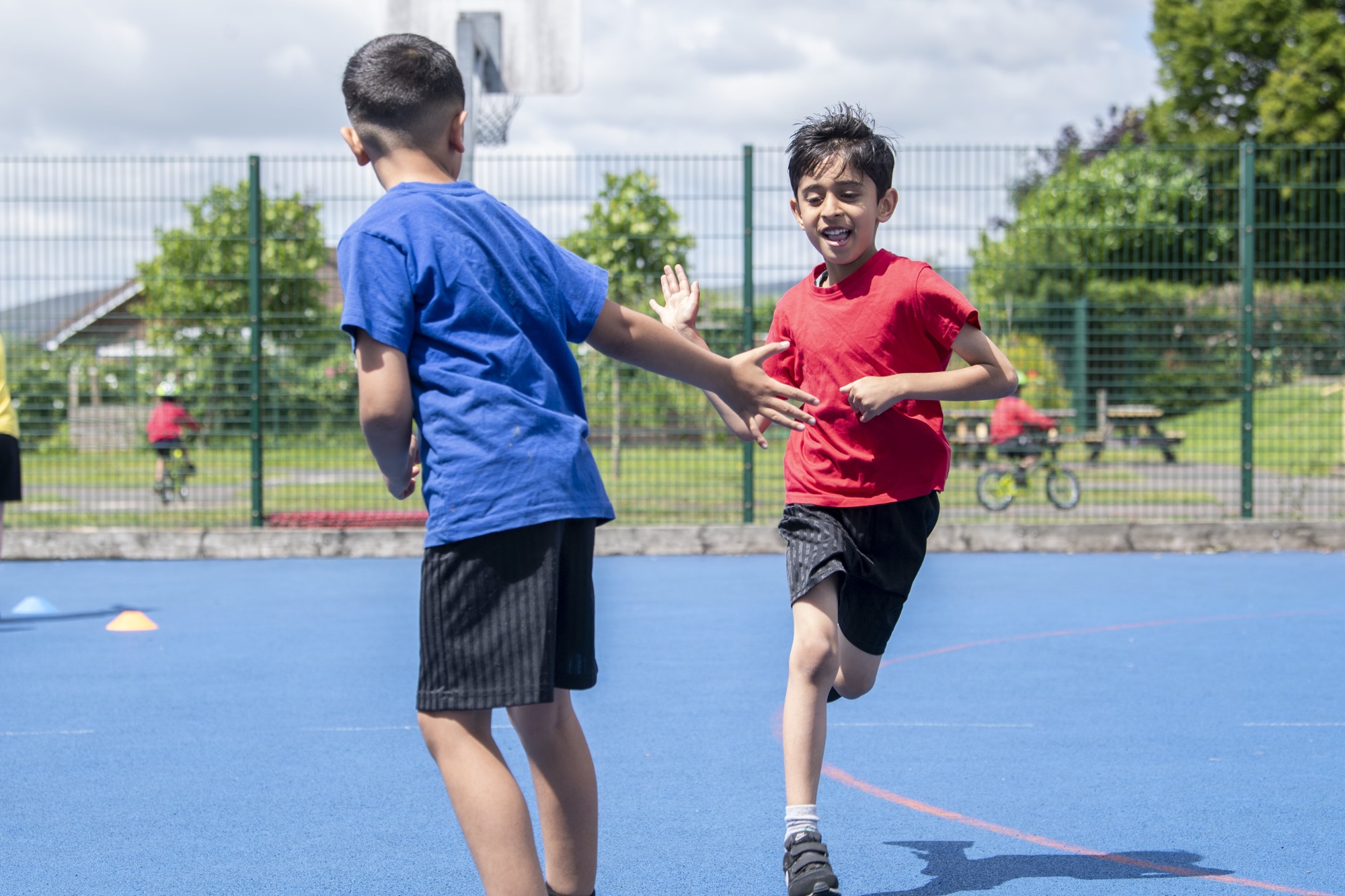 Two boys tapping hands as they run past each other in a PE lesson