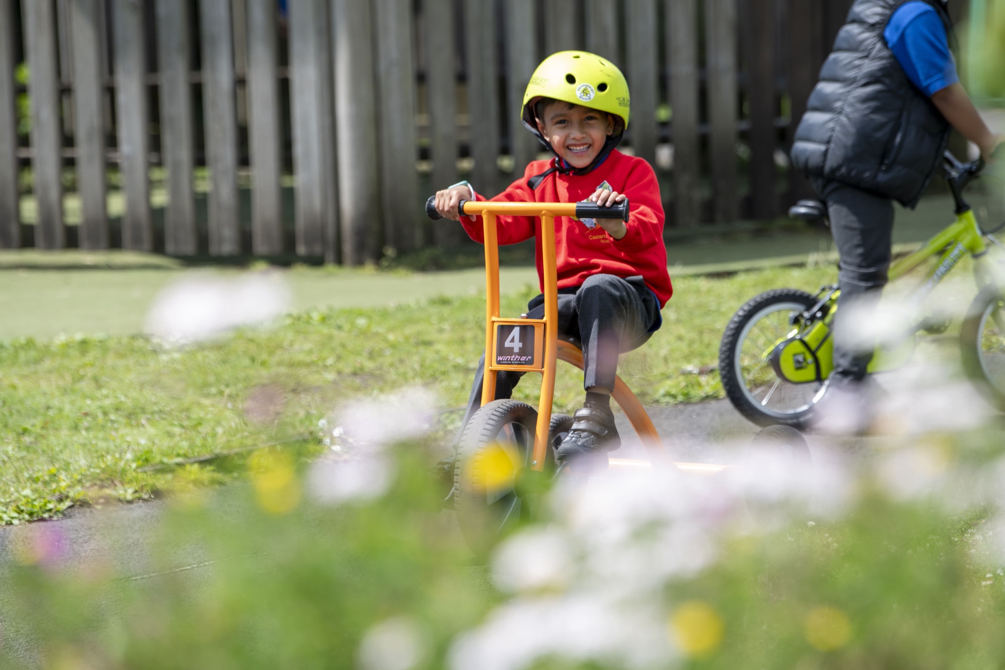 A boy in a yellow helmet on an orange bike